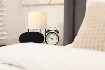 Naklejka premium Alarm clock and sleep mask on nightstand in bedroom