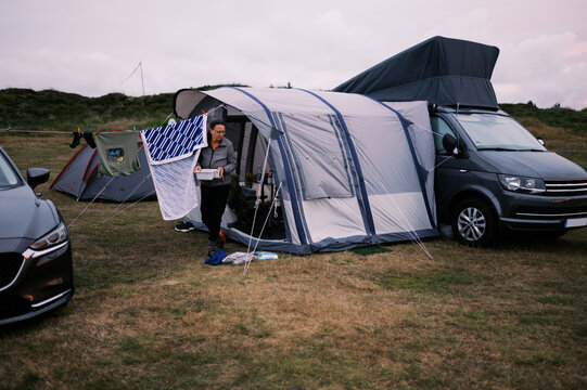 woman coming out of tent holding dishes in bowl