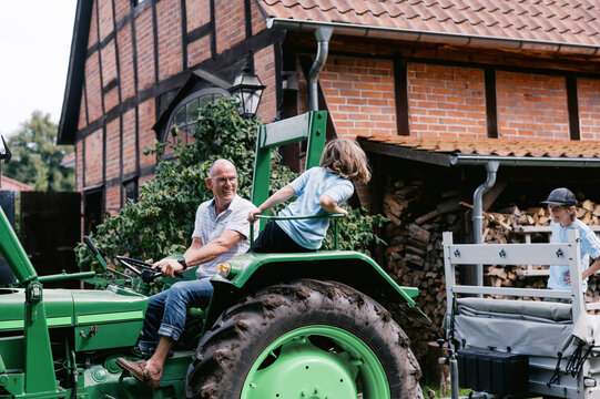 Grandfather and grandkids riding old tractor 