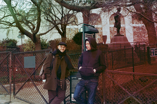 Two man chatting and lying against the fence of a square, Montmartre
