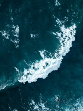 Aerial view of a powerful breaking wave with white foam and deep blue water textures Madeira, Portugal.