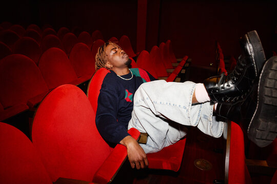 Person relaxes in red theater seat during a movie screening
