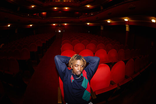 Man relaxes in empty theater seat during evening show
