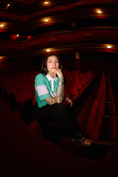 Person sitting in a theater with red seats and warm lights
