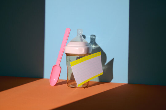 Baby feeding essentials: pink spoon and bottle with note card