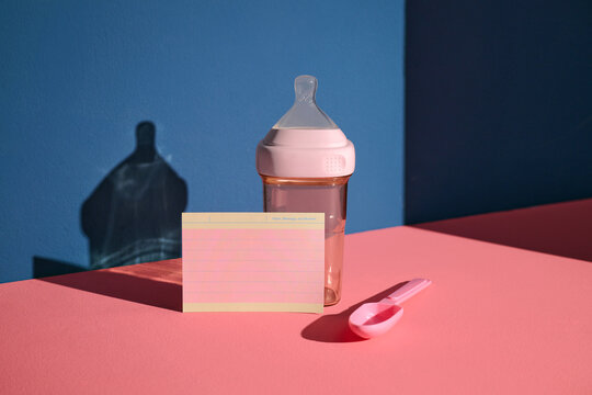 Baby feeding essentials: bottle, spoon, and note card with pink