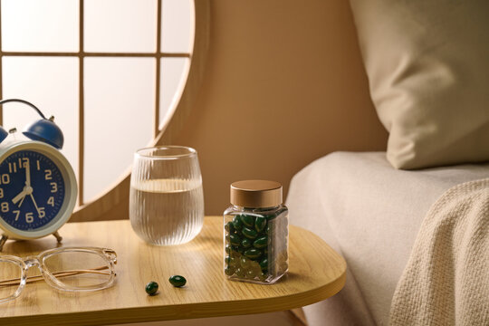 Nightstand essentials with alarm clock, water, supplements, and pills