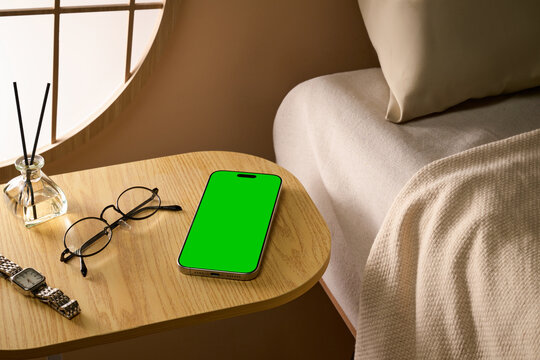 Modern bedside table with a blankscreen smartphone, glasses, diffuser