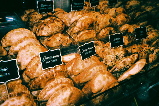 assorted empanadas with labeled fillings on display, 35mm film