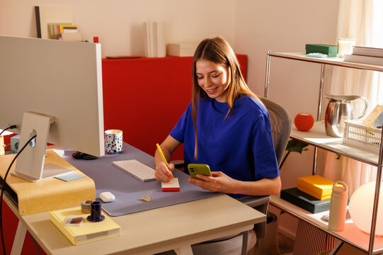 Woman in Blue Shirt Balances Lifestyle at Home Office Desk