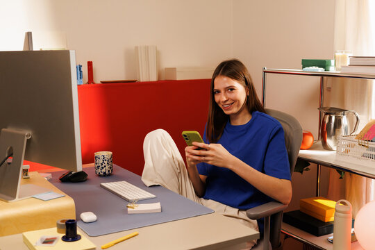 Portrait of a woman in her home office using a smartphone