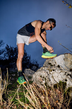Sportsman ties his shoelaces in the wild.