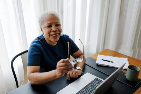 Senior female smiling while working on laptop at home