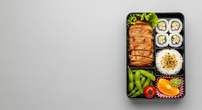 Delicious and healthy Japanese bento box with sushi, teriyaki chicken, and fresh vegetables