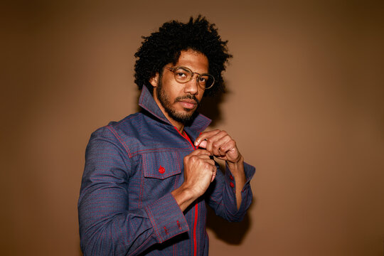 Man Adjusts Jacket in Studio With Plain Background
