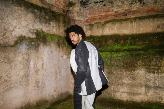 Person Stands in an Old Space Wearing a Unique Outfit at Night