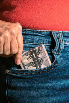 Hand Putting Cash and Smartphone into Blue Jeans Back Pocket
