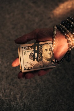 Hand Holding Roll of Hundred Dollar Bills with Money Clip