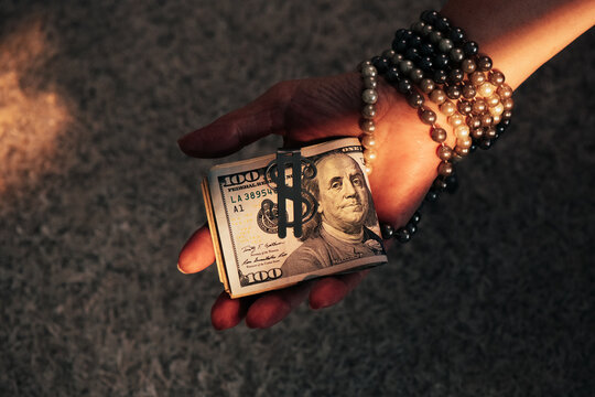 Hand Holding Roll of Hundred Dollar Bills with Money Clip