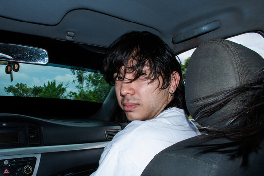 Young Man Looks Back From Passenger Seat While Driving