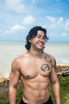 Smiling Man With Tattoos Near the Ocean at Daytime