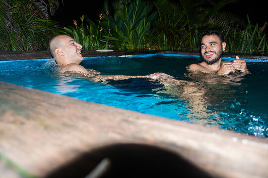 Friends Enjoy Swimming and Talking in a Pool at Night