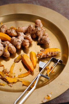 Fresh Turmeric Roots and Slices on a Metal Plate With Peeler