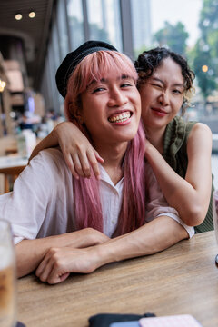 Two friends smiling at a table, one winking.