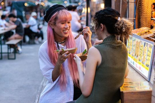Friends enjoy street food at a night market.