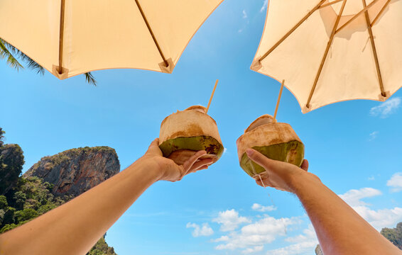 Hands holding fresh coconuts at Railay Beach