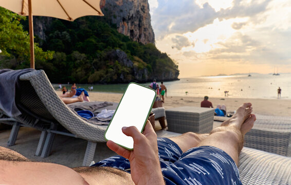 Person holding smartphone while relaxing on beach chair
