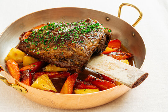 Braised beef short rib with roasted vegetables in copper pan