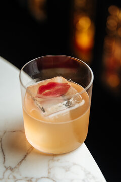 Light cocktail with decorative ice cube and flower petal