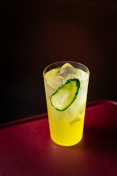 Yellow cocktail with ice and cucumber slice in a glass