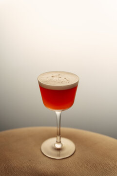 Red cocktail with foam in a coupe glass