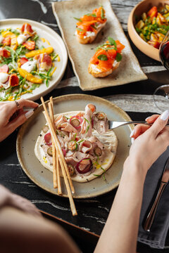 Person eating veal with cream and appetizers at restaurant table