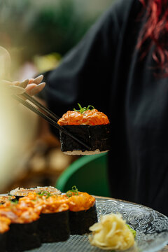 Hand lifting spicy sushi roll with chopsticks