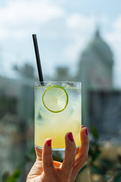 Lime cocktail with ice held in hand outdoors