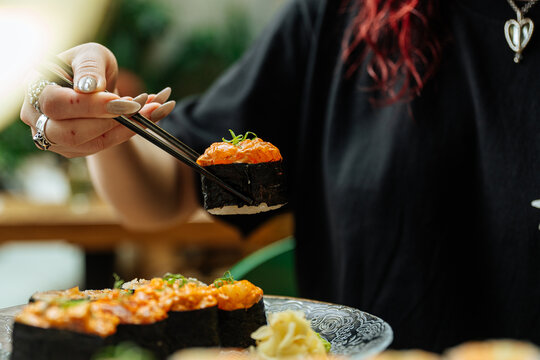 Hand holding spicy gunkan sushi with chopsticks