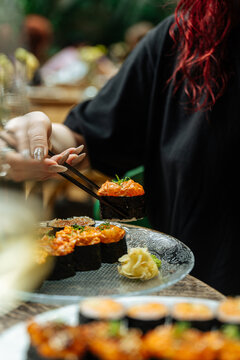 Hand picking spicy gunkan sushi from glass plate