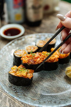 Hand holding spicy sushi roll with chopsticks