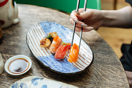 Hand picking salmon nigiri sushi with chopsticks