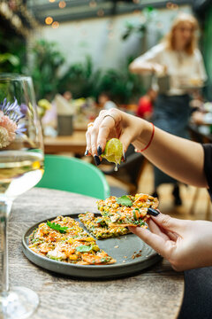 Hand squeezing lime over savory vegetable flatbread