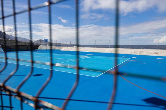 Blue tennis court by the ocean under a clear blue sky in Tenerife.