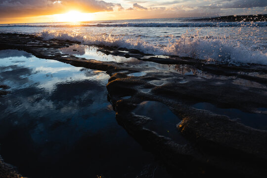 Dramatic ocean sunset with waves and reflections on the shore.