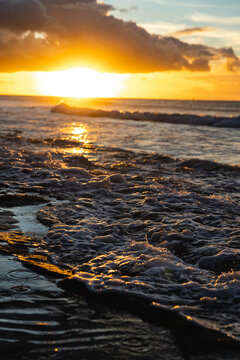 Dramatic ocean sunset with waves and reflections on the shore.