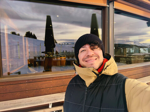 Man taking selfie outside ski lodge in winter clothing