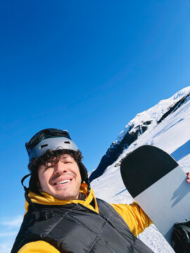Man holding snowboard outdoors on snowy mountain