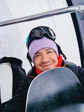 Man holding snowboard inside gondola lift