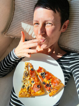 Woman Licking Her Fingers Eating Pizza at Home UGC